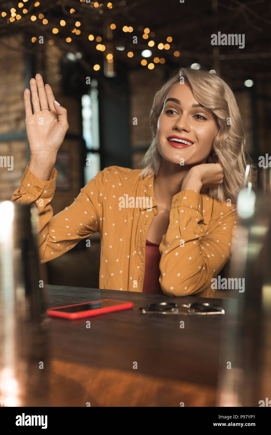Tipsy young woman waving at someone in bar Stock Photo Alamy