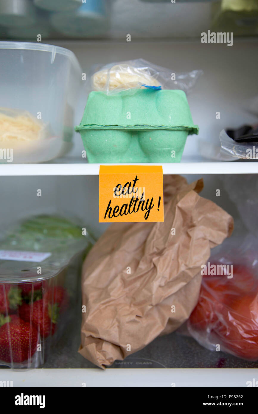 Eat healthy written on a post it note stuck on a fridge shelf with food