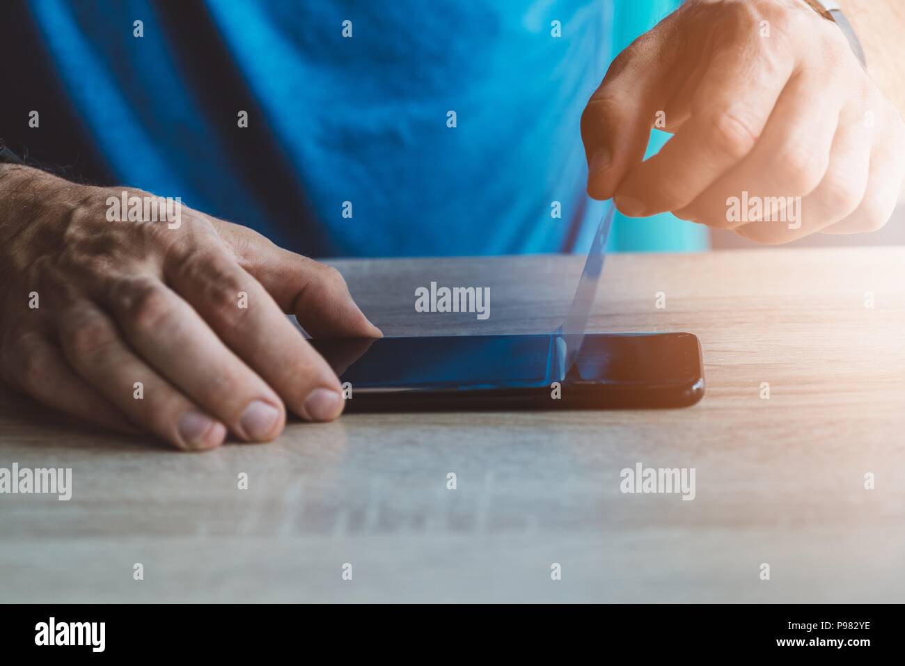 Man applying protective screen protector on his smartphone touchscreen Stock Photo