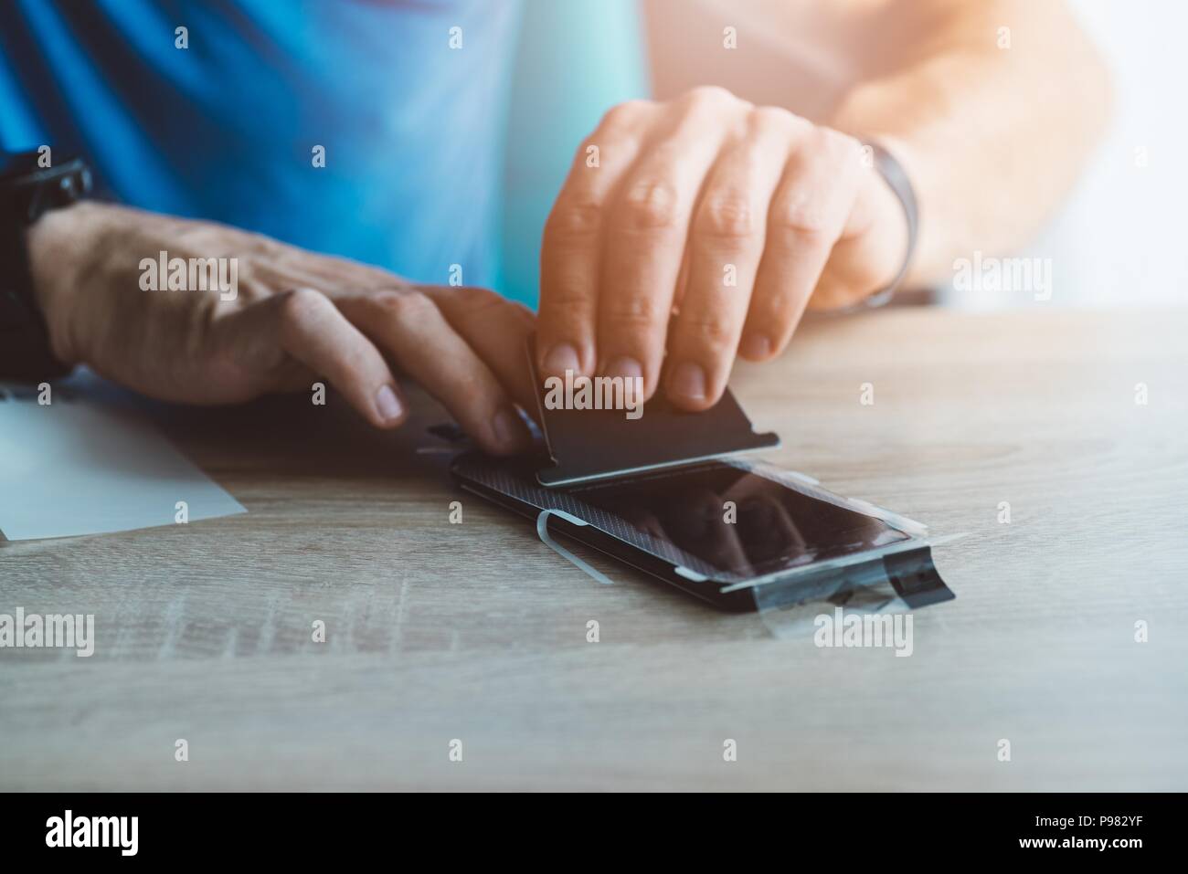Man applying protective screen protector on his smartphone touchscreen Stock Photo