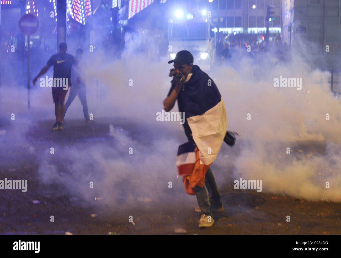 Paris, France. 15th July 2018.French supporters leave the Champs-Elysees avenue after riot police fired tear gas to disperse groups of violent youths. France won the World Cup by beating Croatia 4-2 in the final. Des supporters quittent les Champs-Elysees apres que la police ait utilise des gaz lacrymogenes afin de disperser des groupes violents, suite a la victoire de la France en Coupe du Monde. *** FRANCE OUT / NO SALES TO FRENCH MEDIA *** Credit: Idealink Photography/Alamy Live News Stock Photo