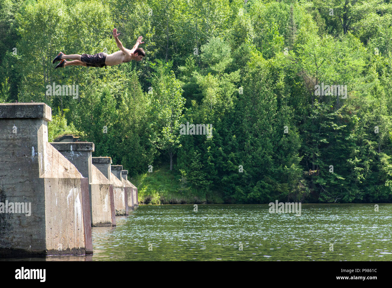 Ottawa, Canada. 15th July 2018. Summer heat: Diving into a river from an abandoned bridge to cool off and beat the heat as temperatures reach into the 30's in Ottawa, Ontario, Canada. Temperatures have been as hot as 36 C since the beginning of July, breaking heat records for the city and surrounding areas. Stock Photo