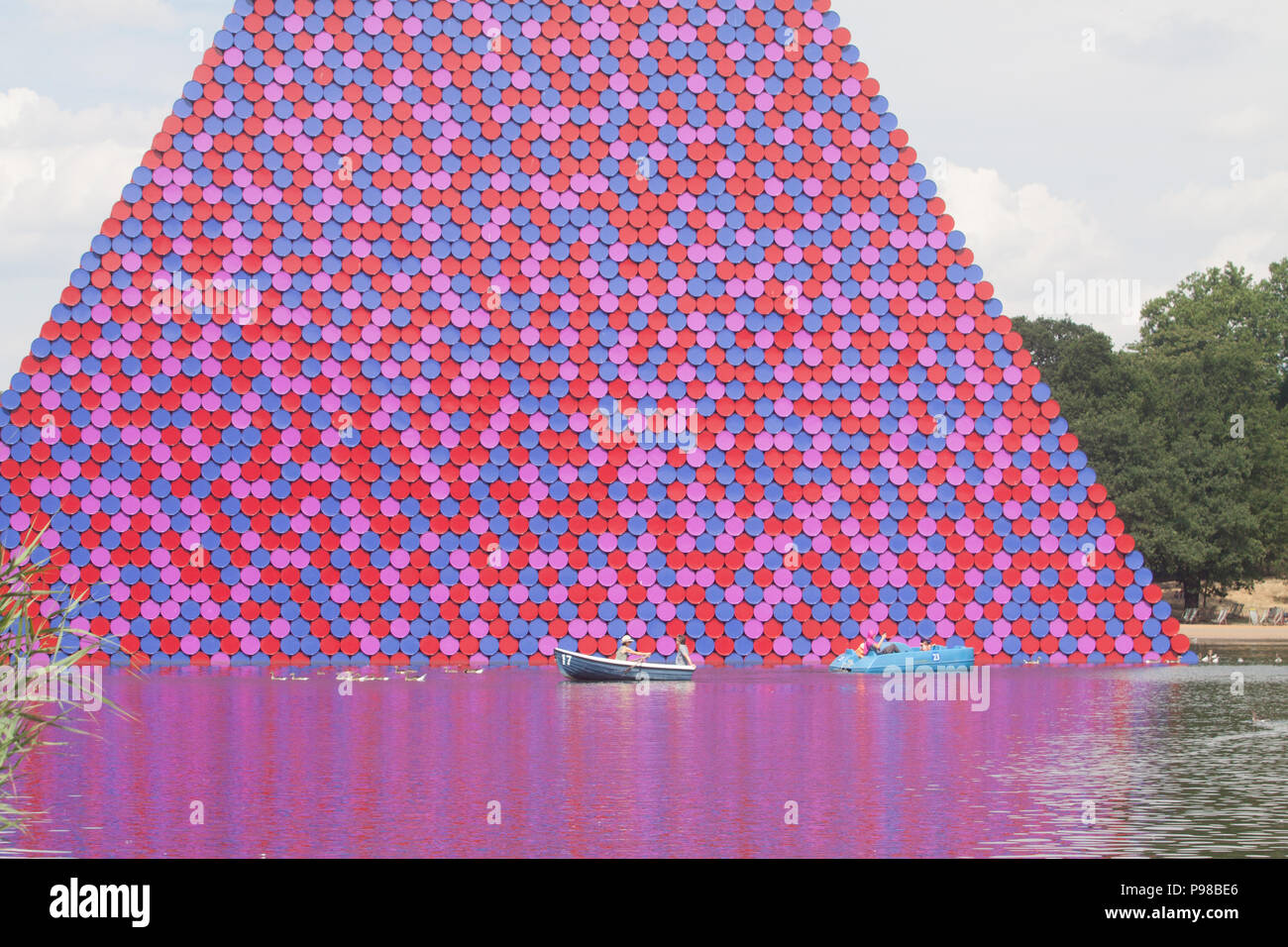 London UK. 16th July 2018. UK Weather: People enjoy paddling on pedalos on the Serpentine in  Hyde Park under blues skies and sunshine  with the backdrop of pyramidal Mastaba sculpture by Christo made of 7000 barrels on another hot day as the ongoing heatwave which has lasted more than 30 days is set to continue Credit: amer ghazzal/Alamy Live News Stock Photo