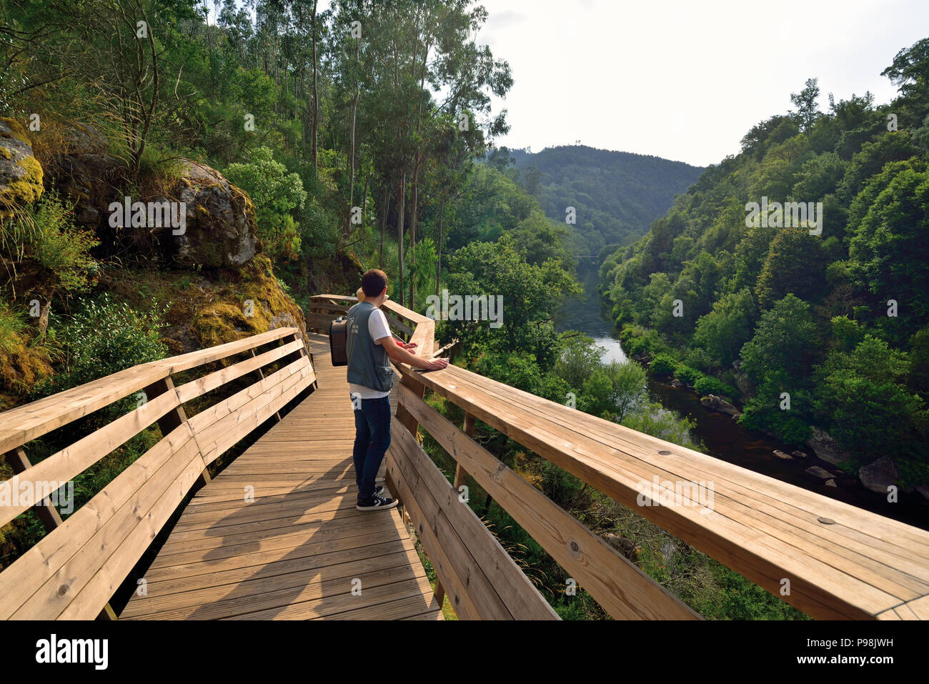 Two people standing on a wooden trail and looking to green river valley Stock Photo