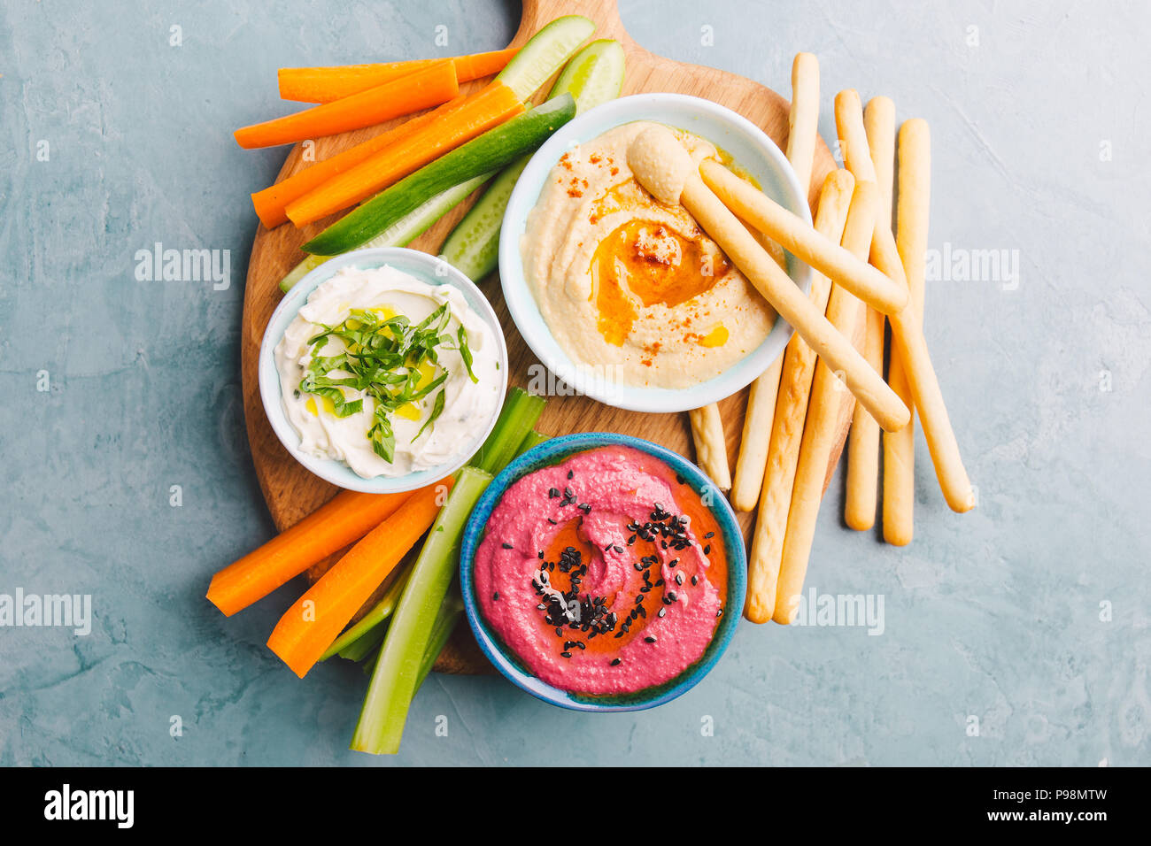 Appetizing vegetarian healthy dips sauces in small bowls with cut vegetables on cutting board. View from above. Healthy detox weight loss concept. Stock Photo