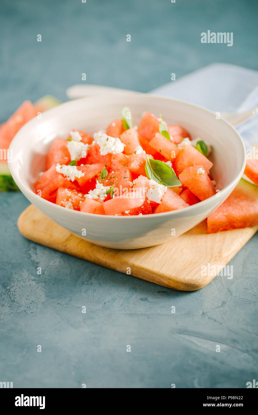 Fresh appetizing summer salad with watermelon cubes, cheese feta and basil in bowl. Served and ready to eat. Clean Detox Weight Loss Concept Stock Photo