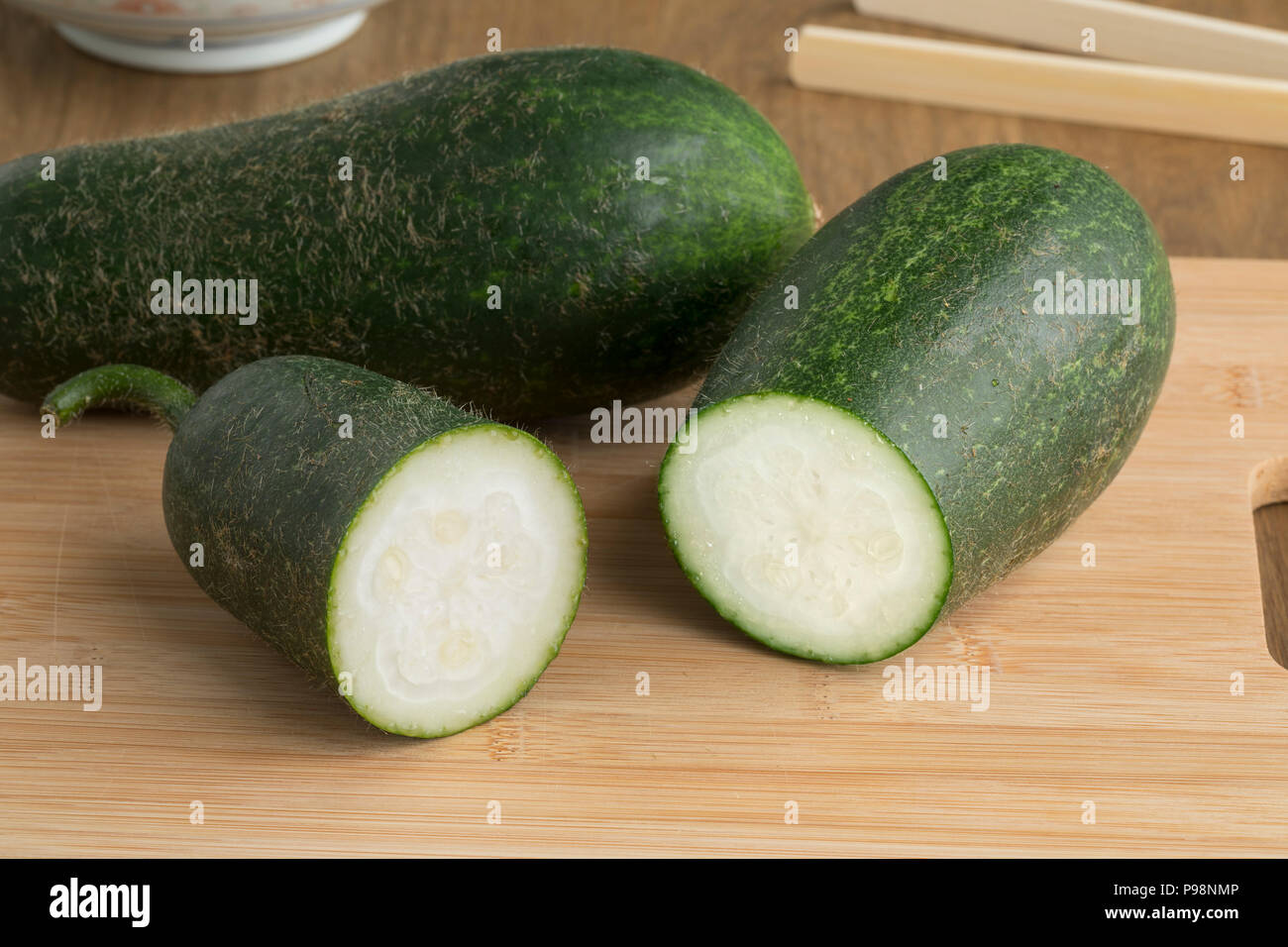 Pair of fresh raw whole and half hairy cucumberon a cutting board Stock Photo