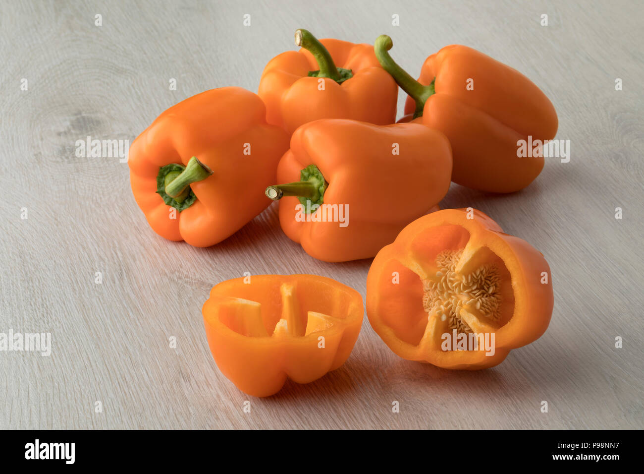 Fresh raw whole and halved sweet orange bell peppers Stock Photo