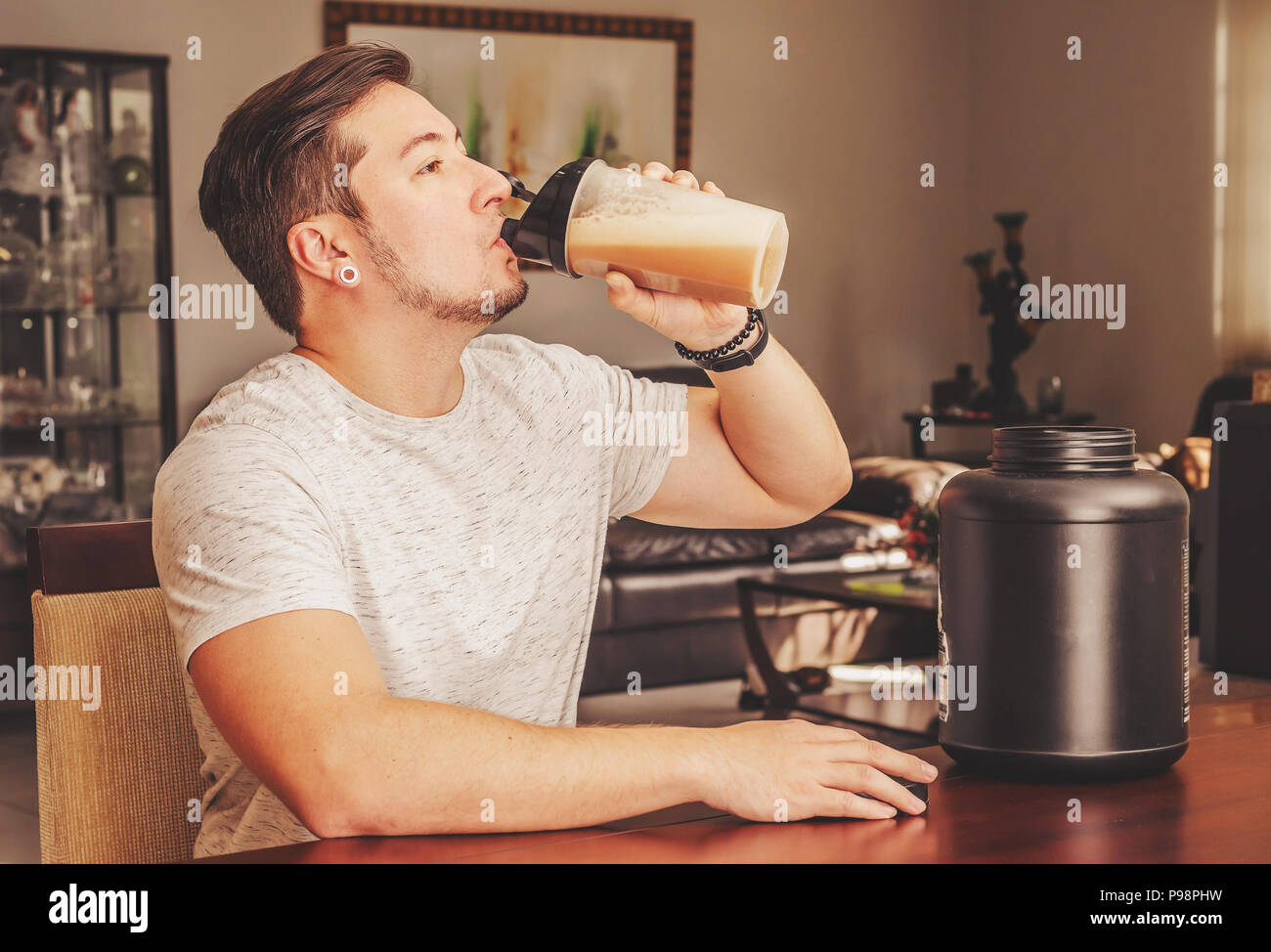 Man drinking whey protein at the blending cup. Post workout protein. Supplement for athletes