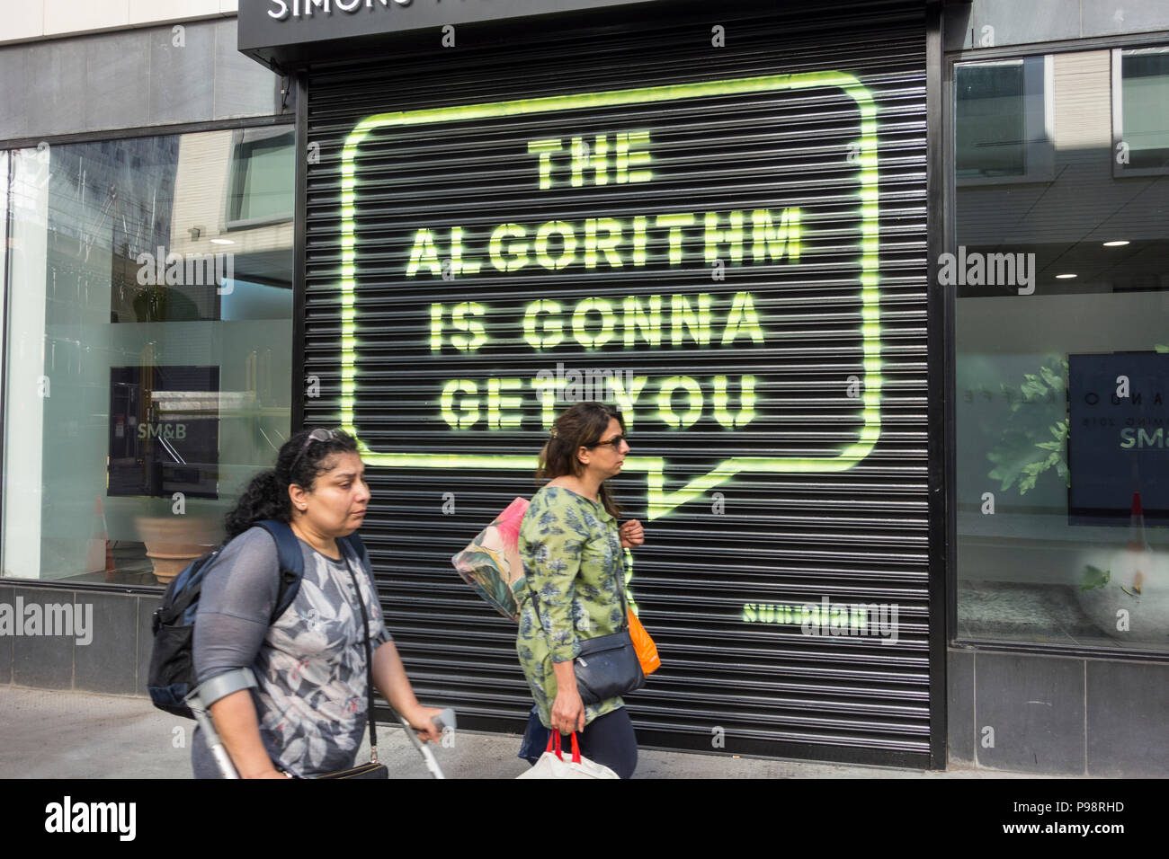 People walking past the Algorithm Is Gonna Get You by Subdude, opposite Facebook's Rathbone Square HQ, in London, England, UK Stock Photo