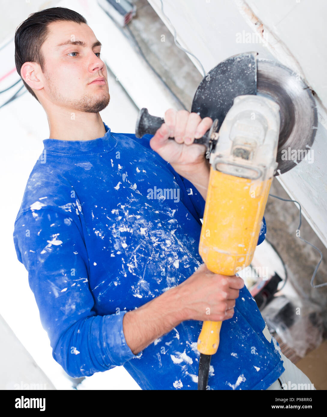 Construction worker cutting concrete wall by using handheld circular saw Stock Photo