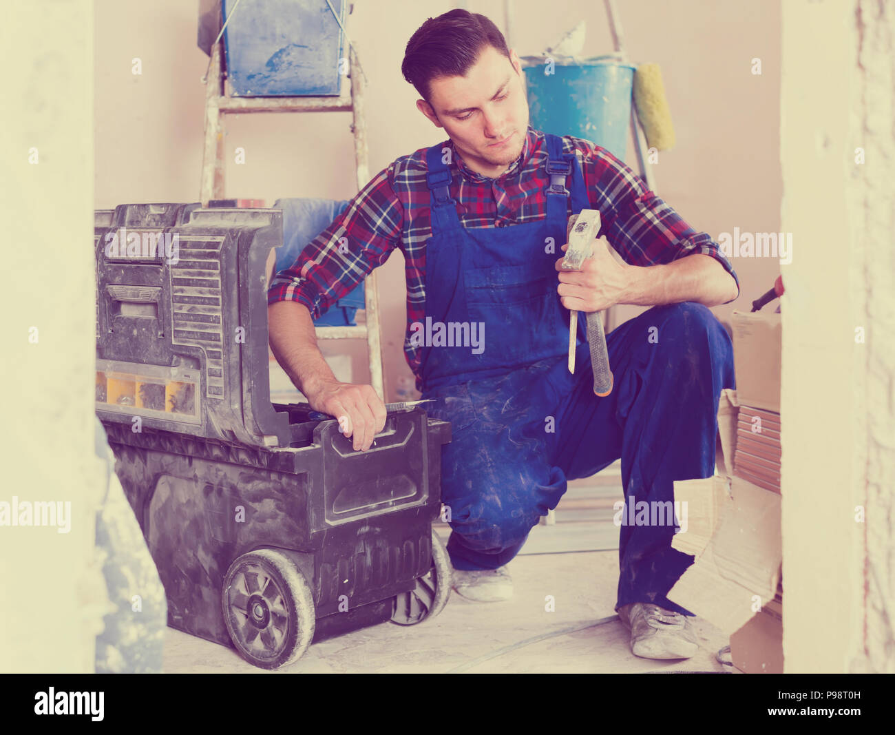 attentive builder handyman choosing necessary tool in toolbox Stock Photo