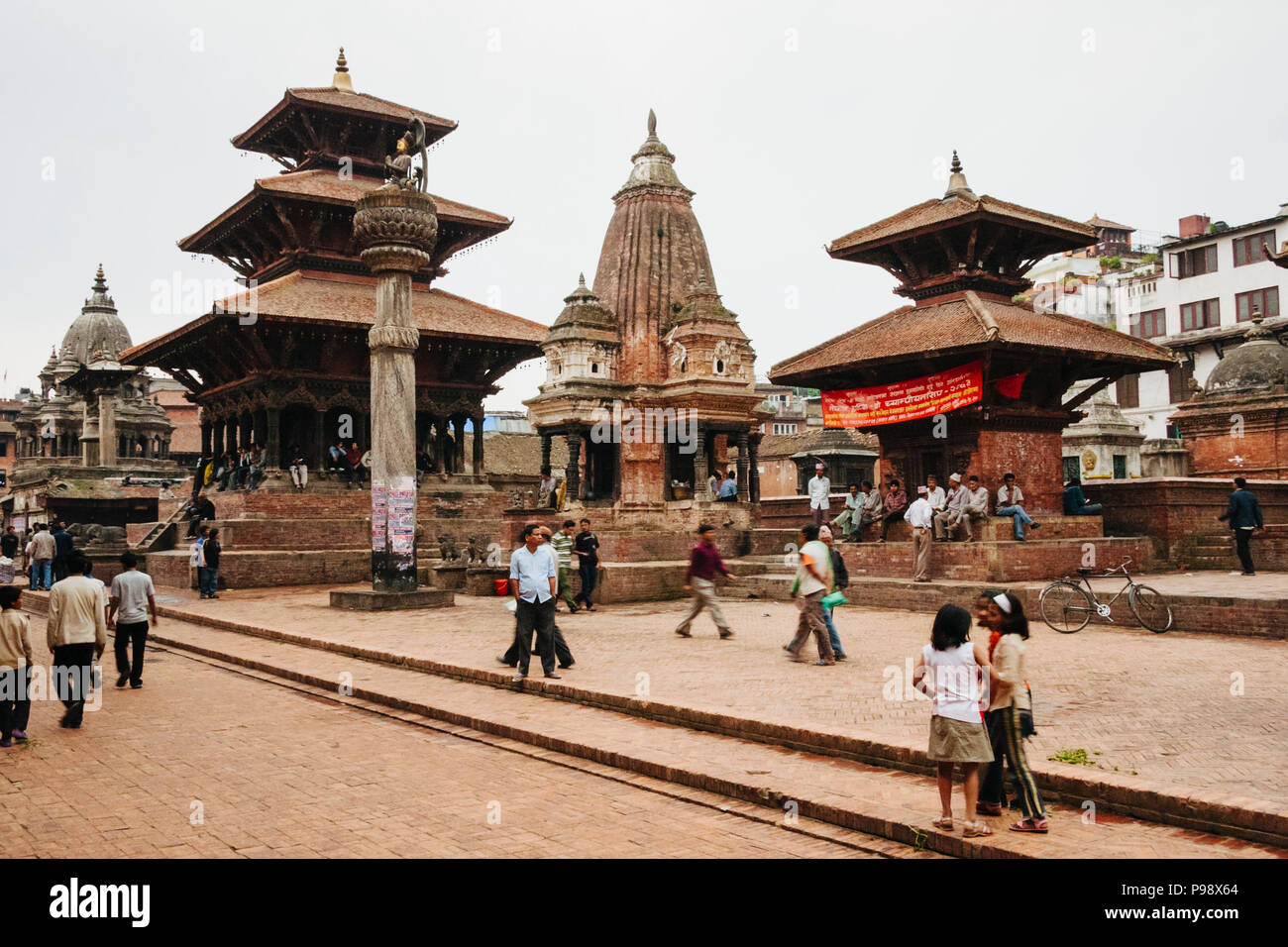 Lalitpur, Kathmandu Valley, Nepal : Passersby walk along the Unesco listed Patan Durbar square. Bhimsen, Vishwanath and Krishna temples are seen in ba Stock Photo