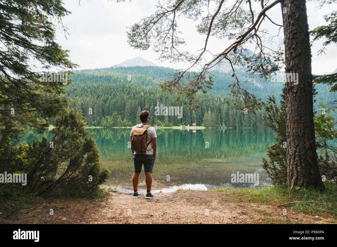 A male tourist stops to admire the perfectly clear, still lake in Durmitor National Park, Montenegro Stock Photo