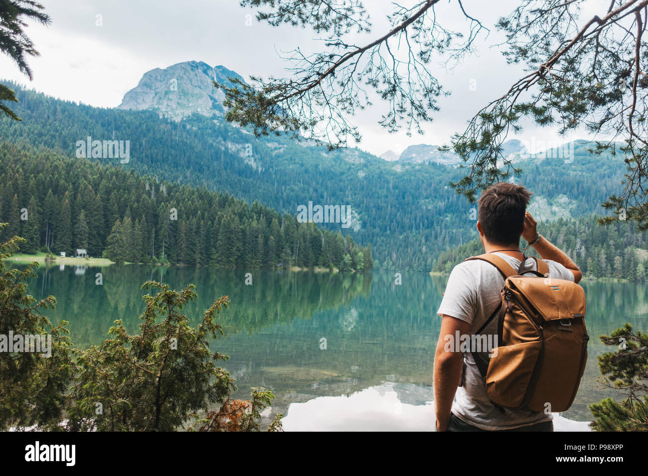 A male tourist stops to admire the perfectly clear, still lake in Durmitor National Park, Montenegro Stock Photo