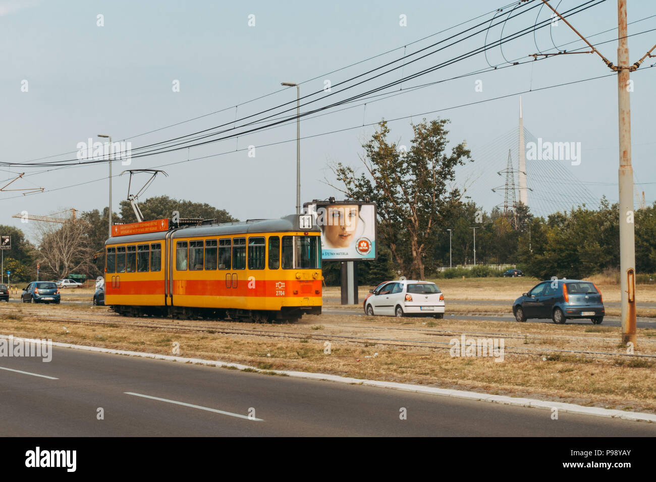 A tram passes traffic in the median of an arterial road in Belgrade, Serbia Stock Photo