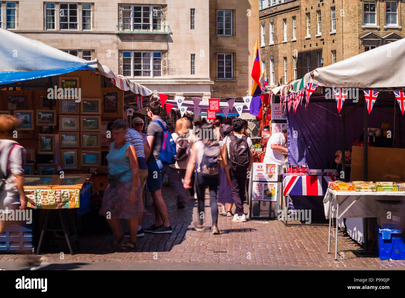 People browsing and walking past outdoor market stalls in Market street, Cambridge, UK Stock Photo