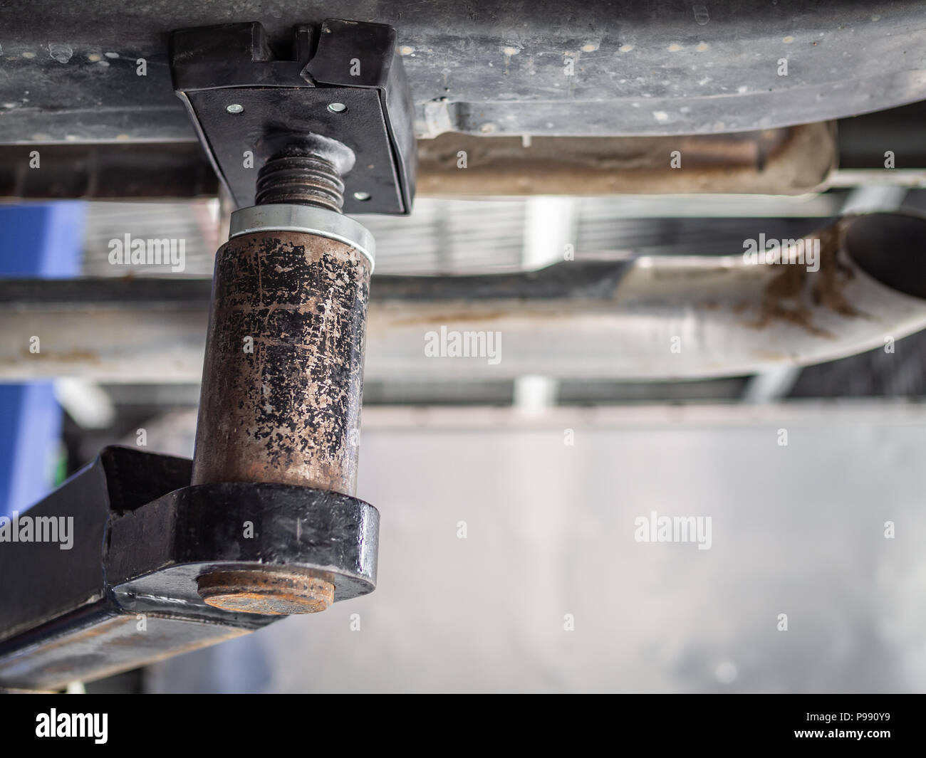 Close-up detail of car repair lift machine in automobile service garage, under the car view with copy space. Stock Photo