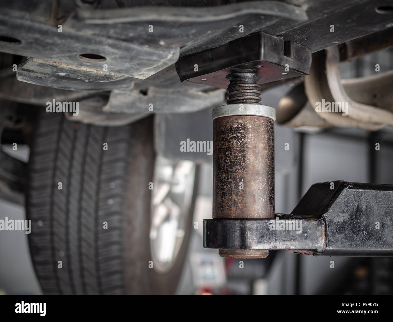 Close-up car repair lift machine in automobile service garage, under the car view. Stock Photo