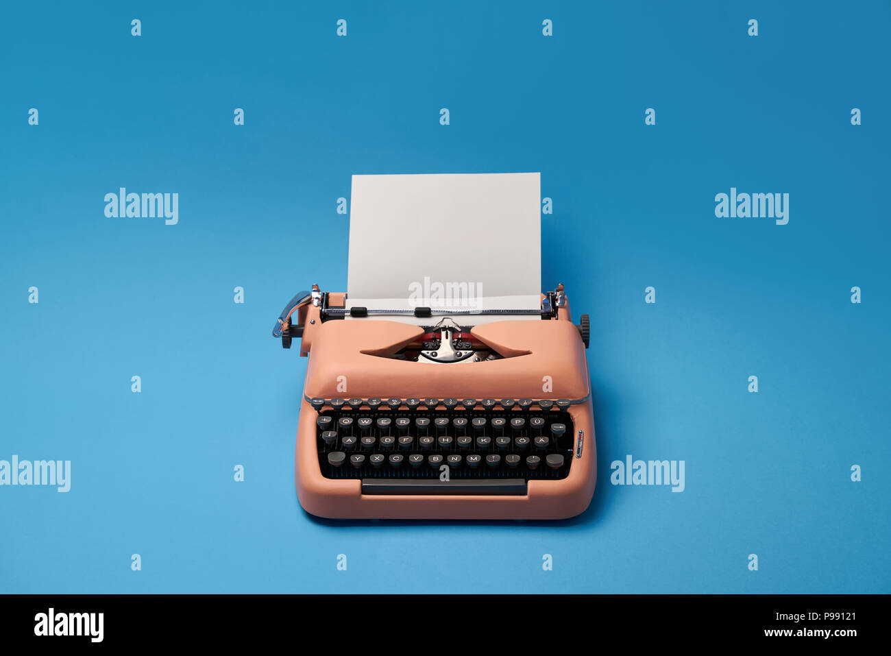 Old typewriter with a paper sheet on the blue background in the studio. Horizontal. Stock Photo