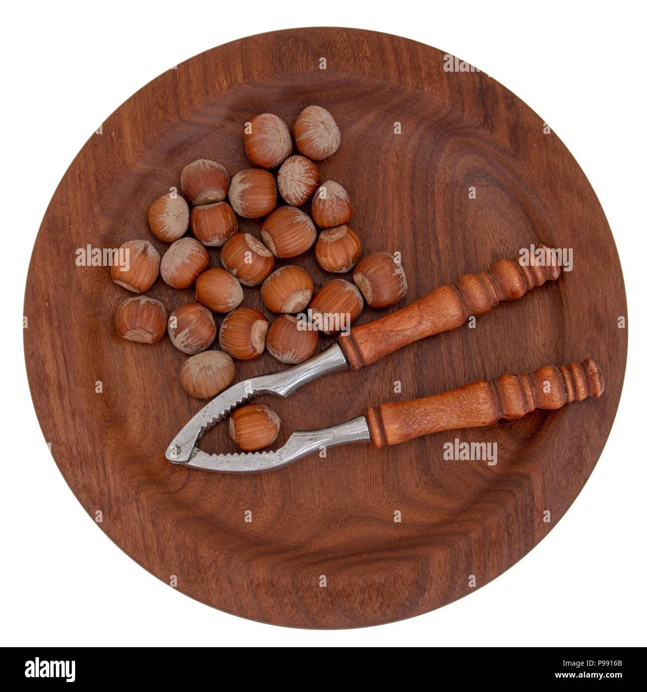 Nutcrackers and hazelnuts on beautiful wooden plate, isolated on white. Typical Christmas, seasonal treat. Stock Photo