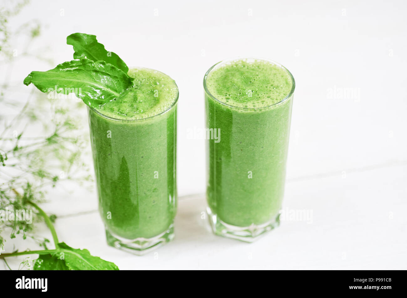 Blended green smoothie with ingredients or cocktail on white background, breakfast vegan with a place for your text, concept of raw food Stock Photo