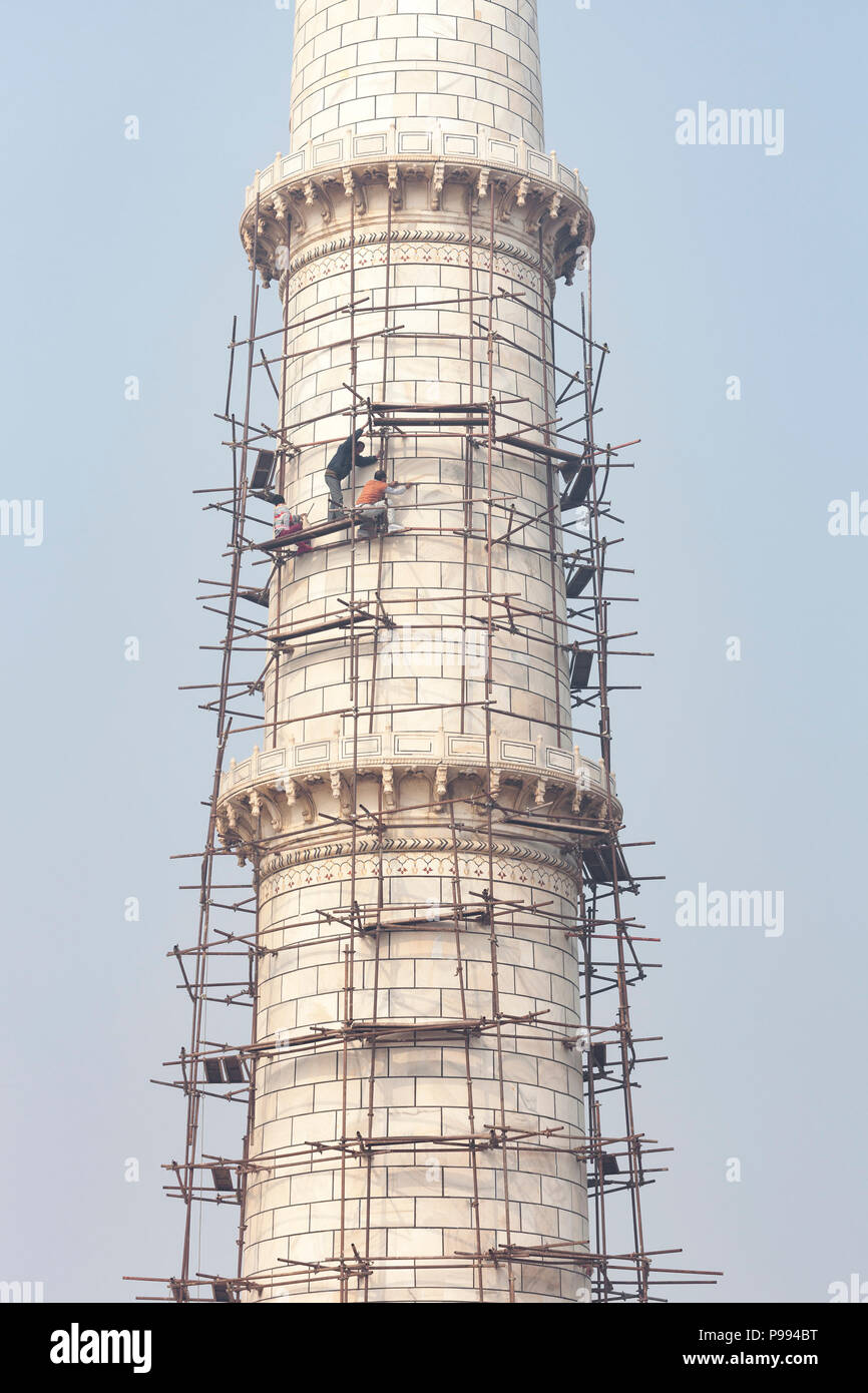 AGRA, INDIA - JANUARY 13, 2015 : Craftsmen on a high scaffold repairing the marble facade of the north east minaret at the Taj Mahal. Stock Photo