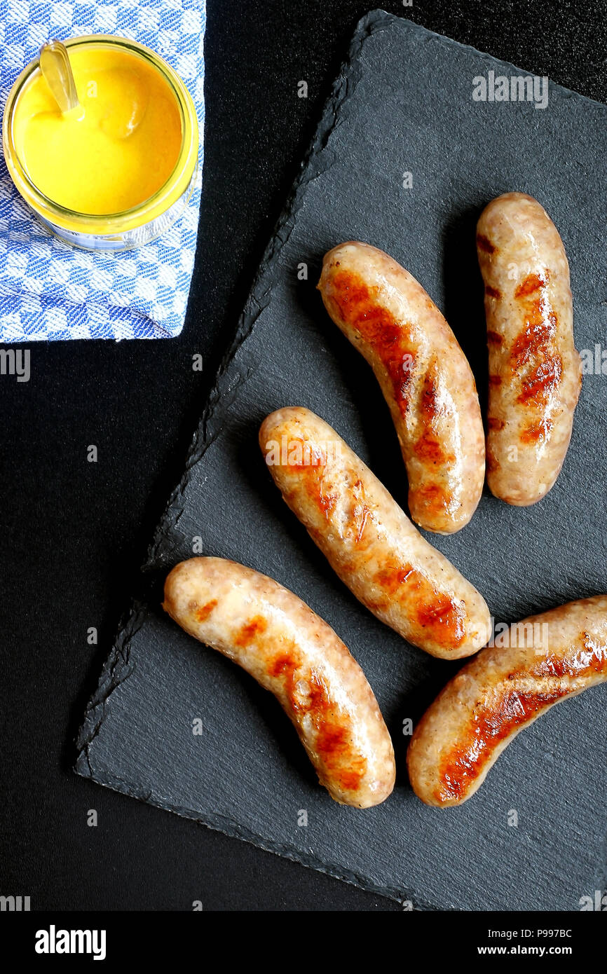 Hot Grilled German Bratwurst on Slate Board served with Mustard Stock Photo