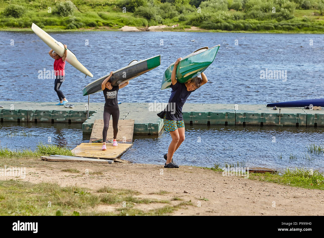 Polotsk, Belarus - July 6, 2018: After termination to rowing training, young athletes have got kayaks from water and carry them on coast on shoulders, Stock Photo