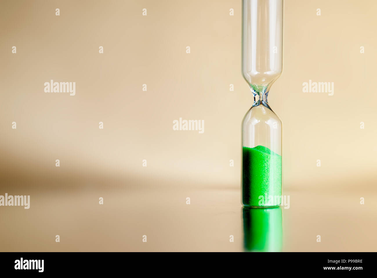 Modern beautiful green hourglass with bright background for copy space. Hourglass time passing concept for business deadline, urgency and running out of time. Stock Photo