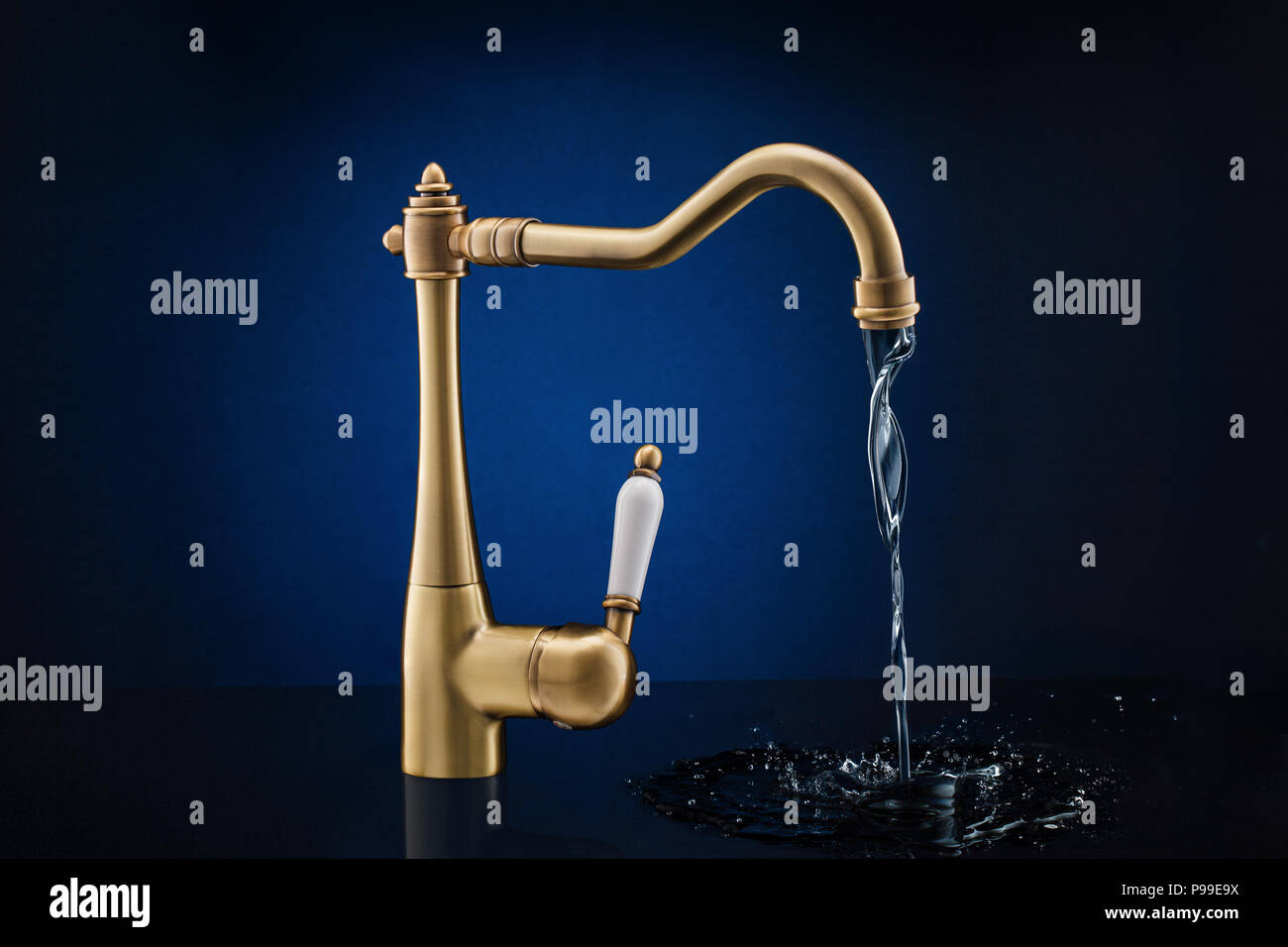 Modern kitchen faucet against dark blue background. Stock Photo