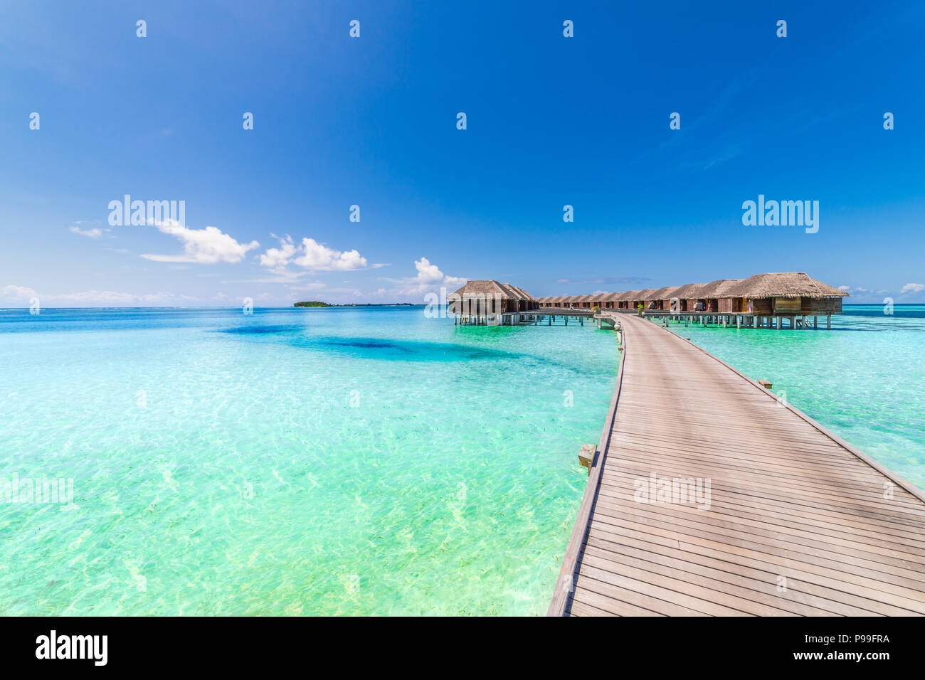 Maldives island, luxury water villas resort and wooden pier. Beautiful sky and clouds and beach background for summer vacation holiday and travel Stock Photo