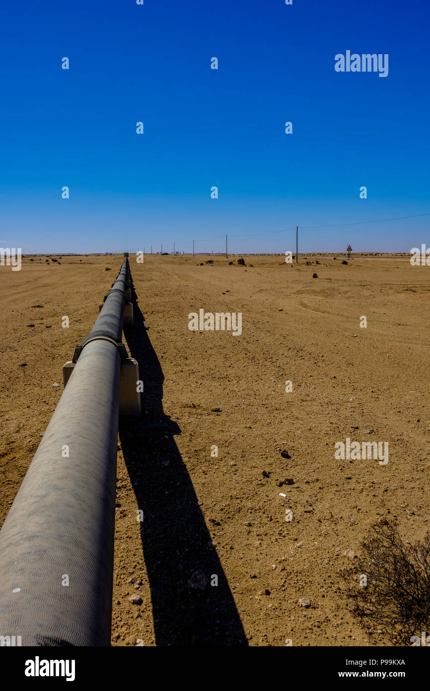 Above ground iron pipe stretches into distance in Namib Desert carrying water supply from desalination plant in Swakopmund to uranium mine. Part of Ch Stock Photo