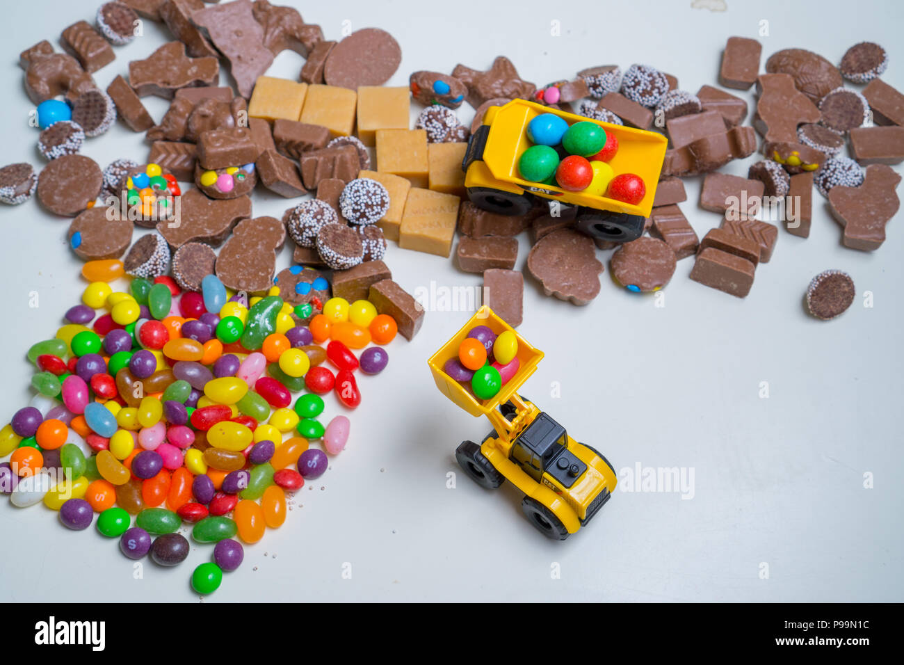 Toy dump trucks moving chocolate and candy around Stock Photo Alamy