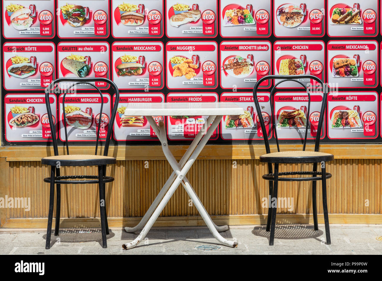 Two chairs and a metal table, on the pavement outside a fast food restaurant,Brussels, Belgium Stock Photo