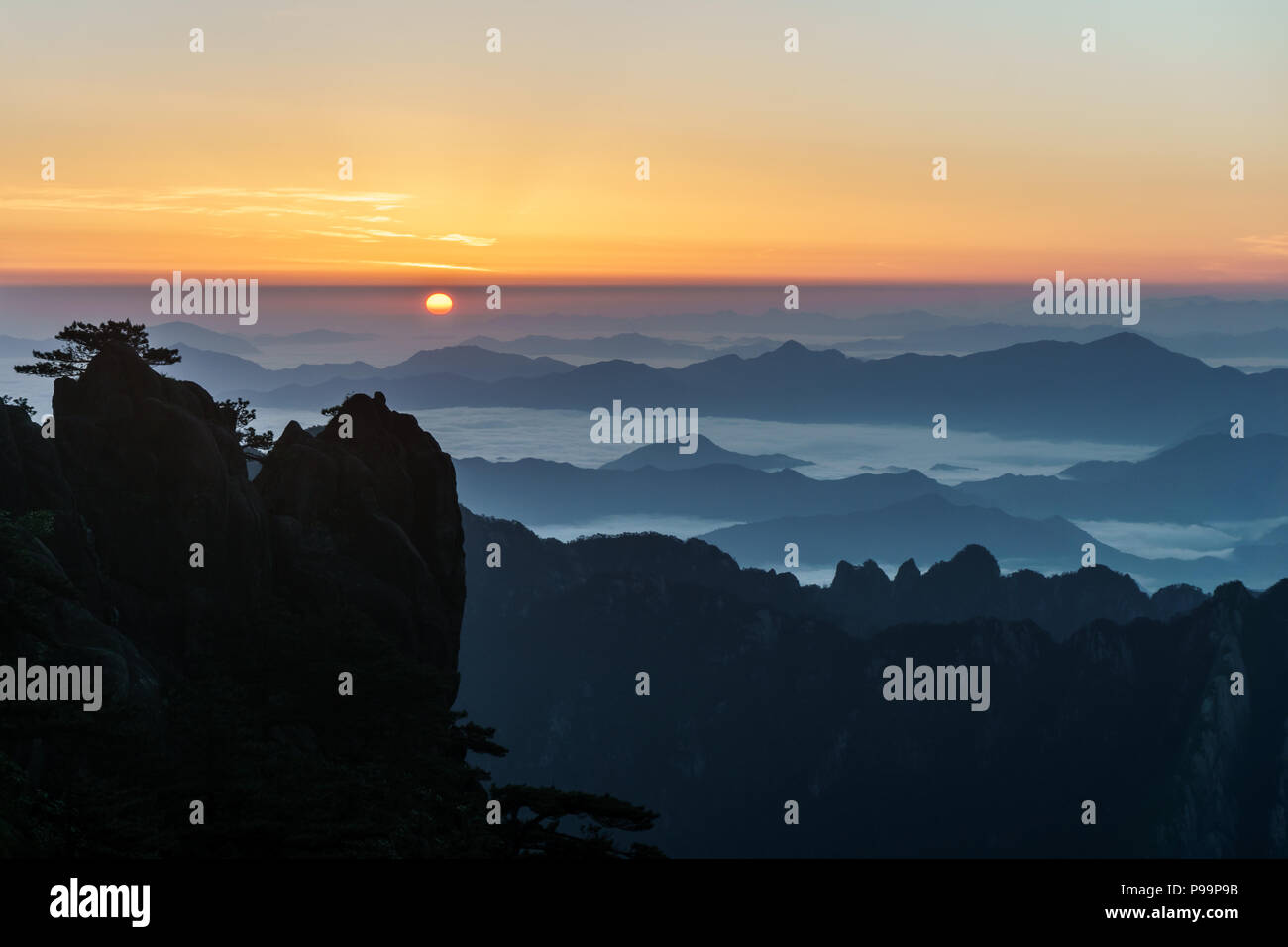 Sun rising from eastern smog over the sea of clouds in Huangshan mountain range in southern Anhui province in eastern China. Stock Photo
