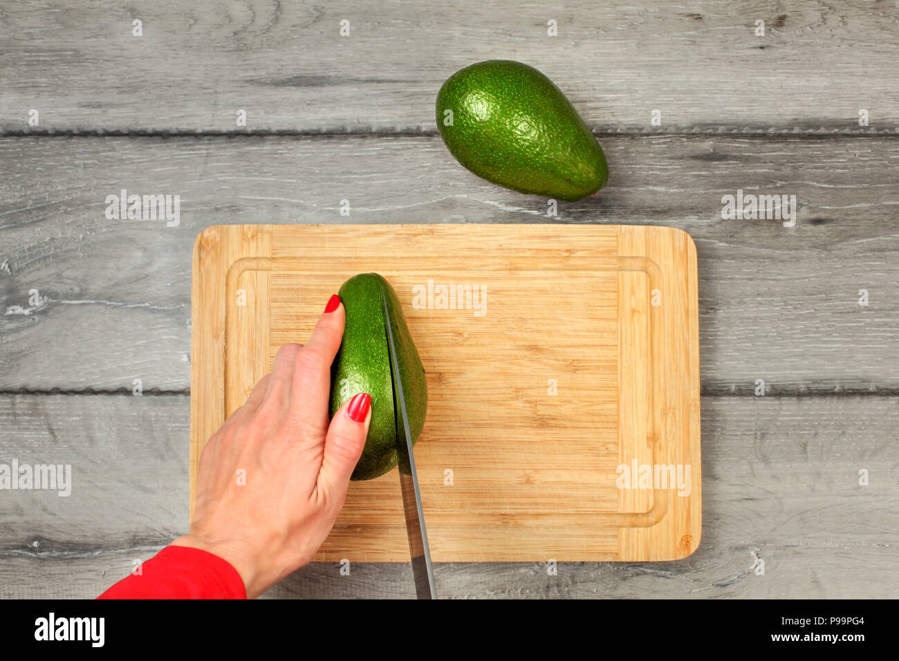 Royalty-Free photo: Avocado fruit on chopping board beside green handled  knife