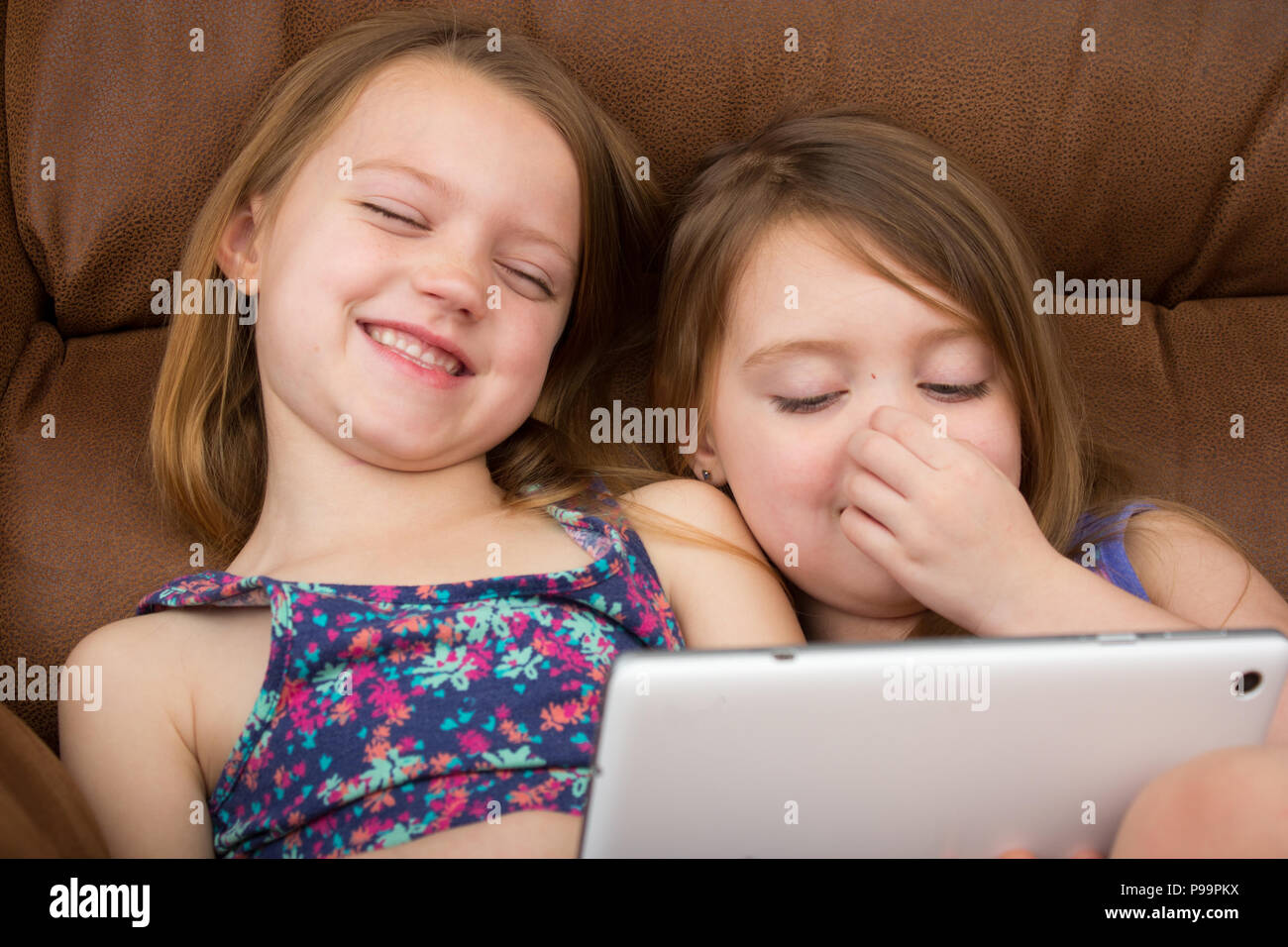 Two girls watching a tablet and laughing Stock Photo