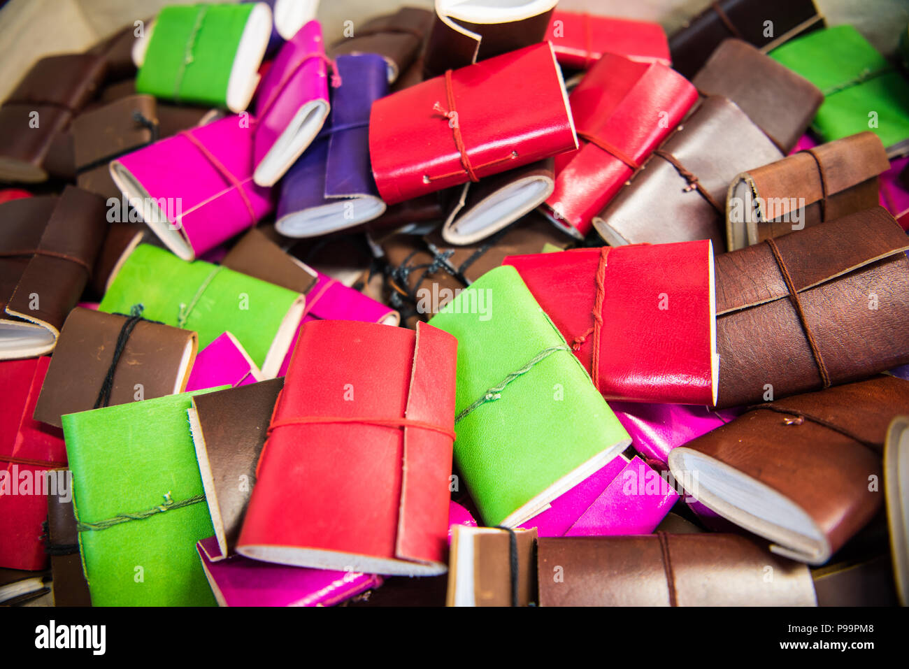 Handmade leather bound colourful notebooks piled up on a market stall  in the historic city of Bath, England, UK Stock Photo