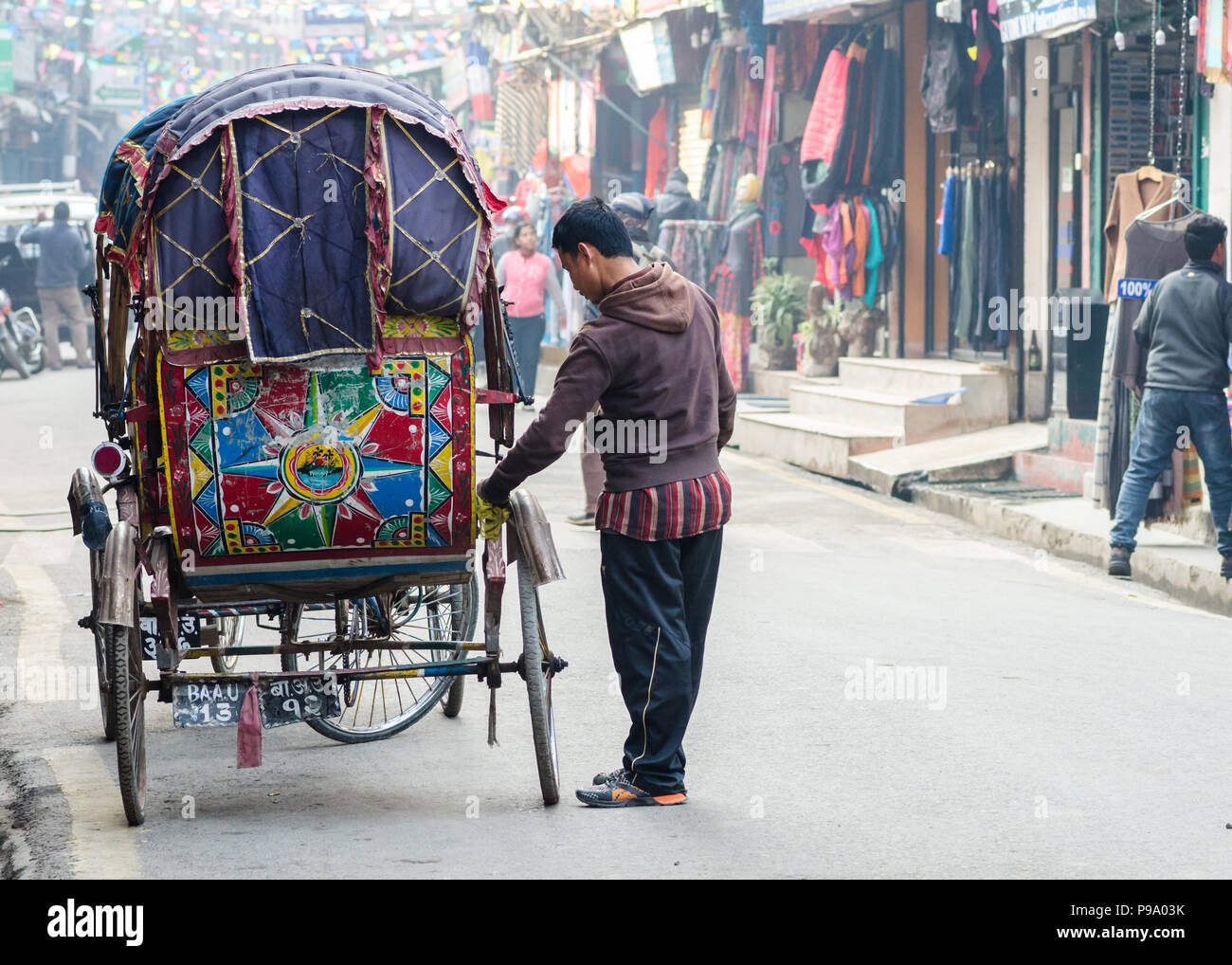 Nepali man cleaning his colorful rickshaw in Thamel, Kathmandu, Nepal Stock Photo