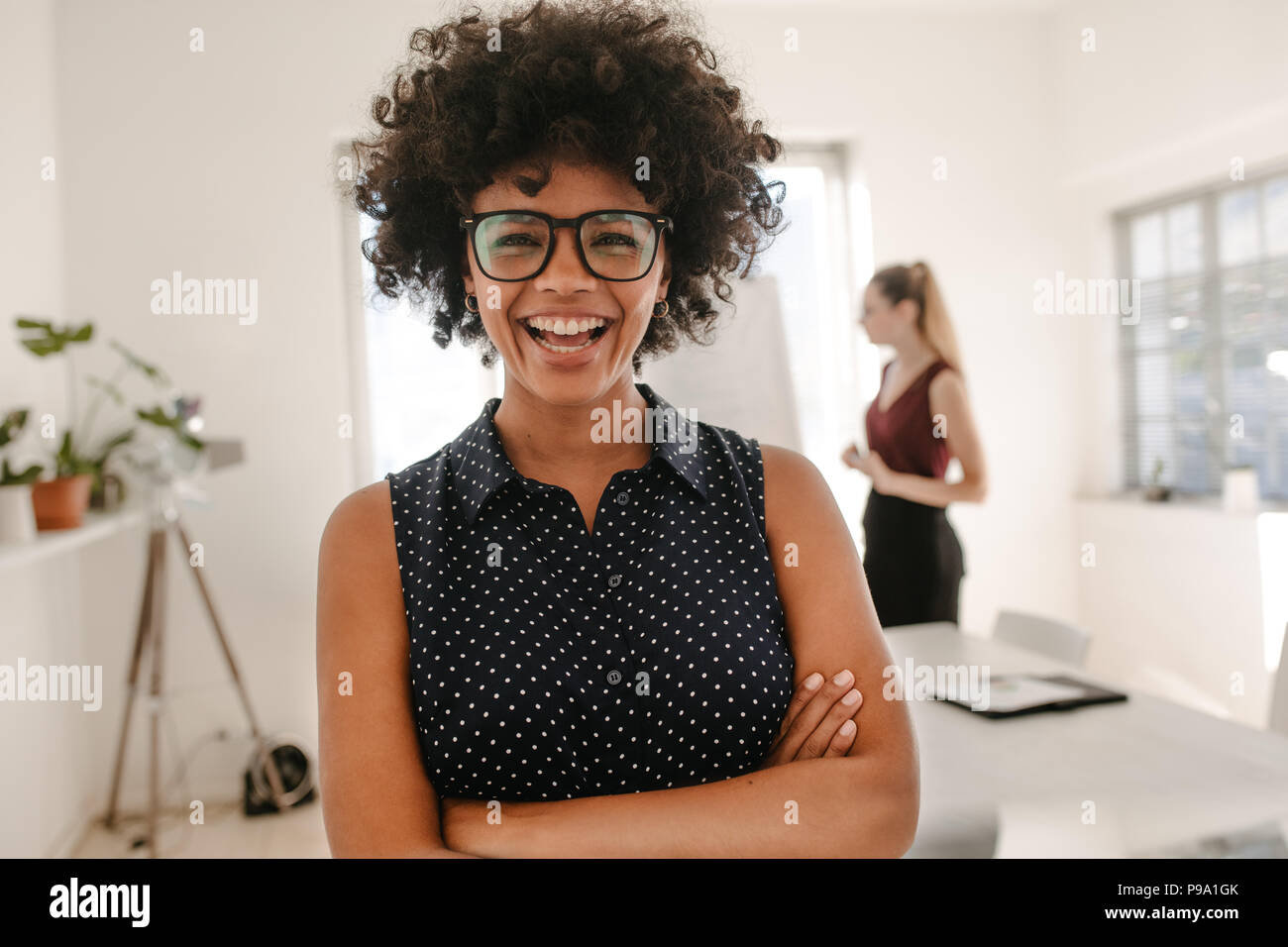 Portrait of young african businesswoman standing with her arms crossed ...