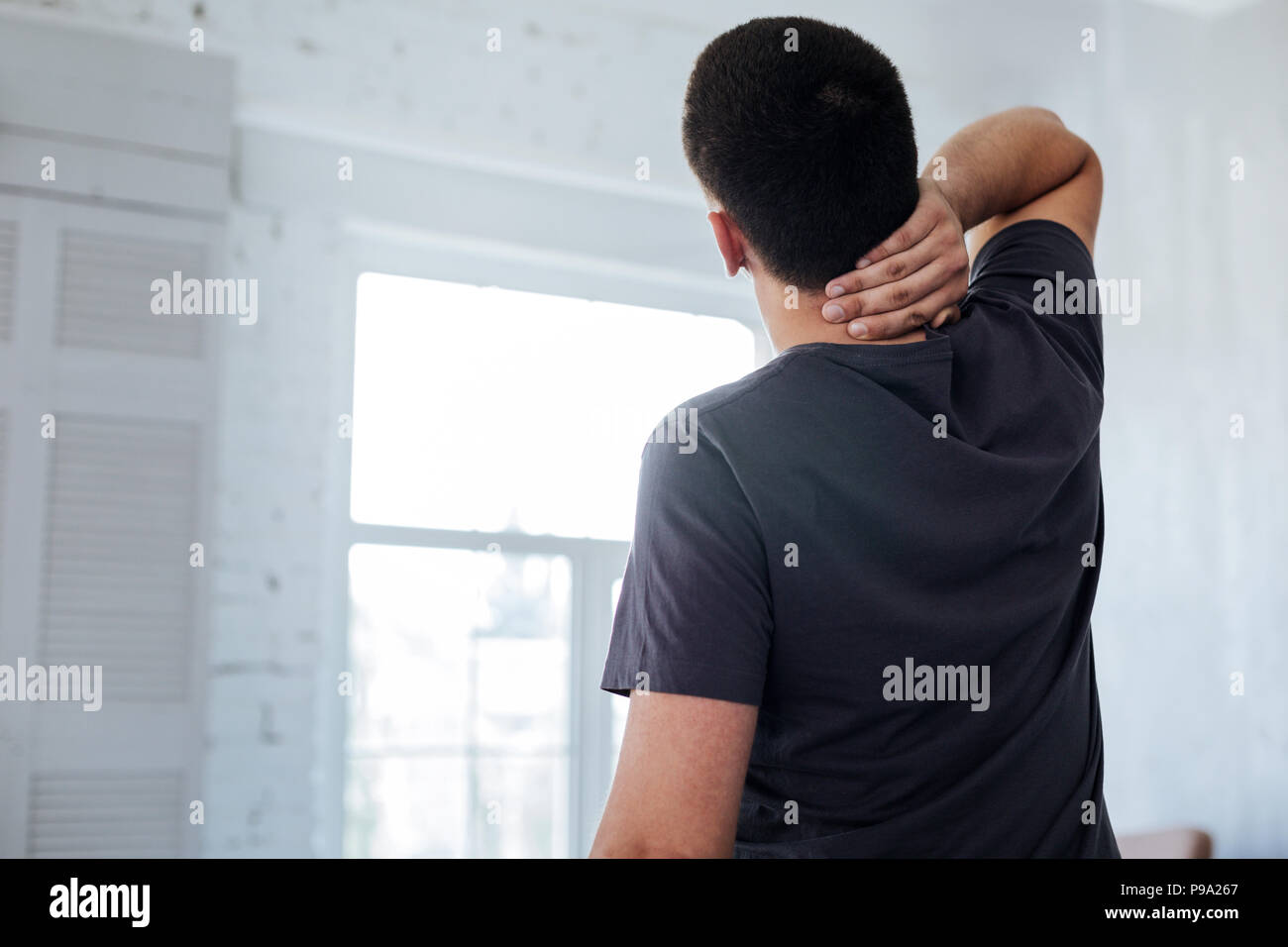 Dark-haired man holding his neck Stock Photo