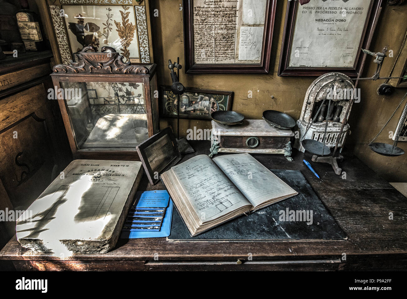 The work table of the pharmacist with weight scales and a copybook in the back room of the main hall of the old Pharmacy and Apothecary 'Farmacia di S. Maria della Scala' in Piazza della Scala in Trastevere quarter, Rome, Italy Stock Photo