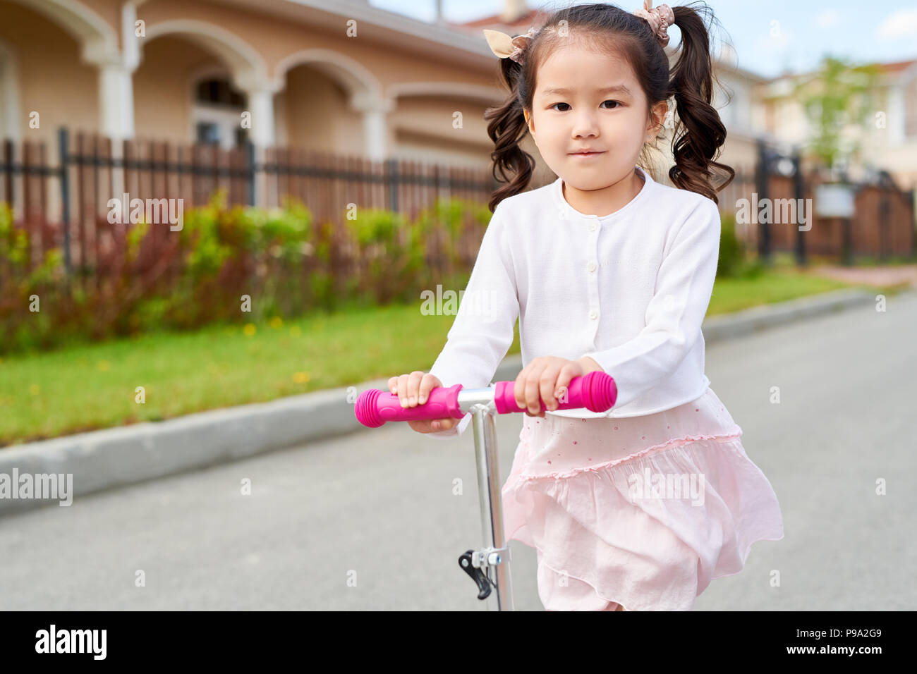 Little Asian Girl Riding Scooter Stock Photo