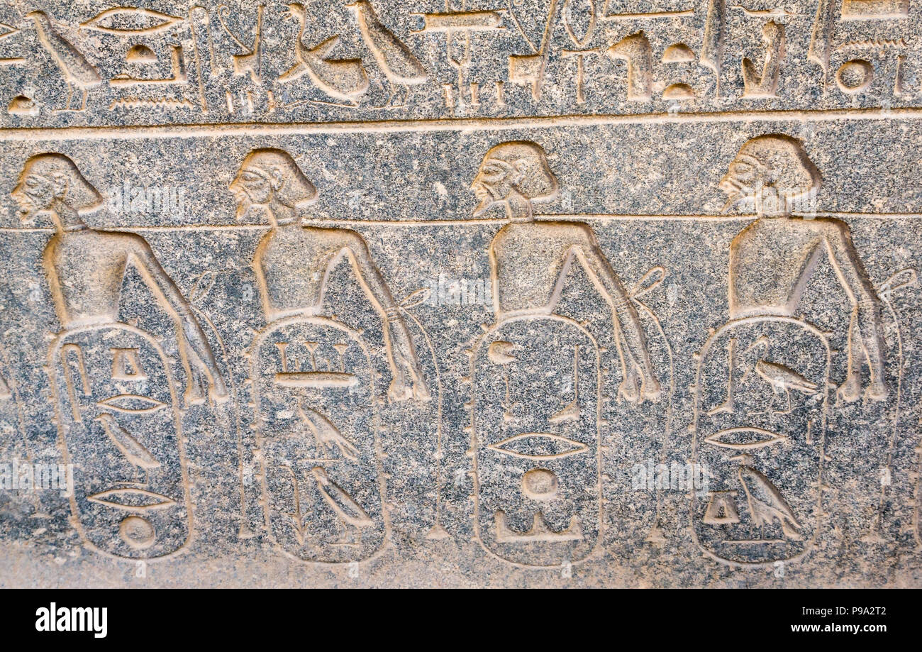 Close up detail of Ancient Egyptian carved figures hieroglyph with Greek script graffiti, Luxor Temple, Luxor, Egypt, Africa Stock Photo
