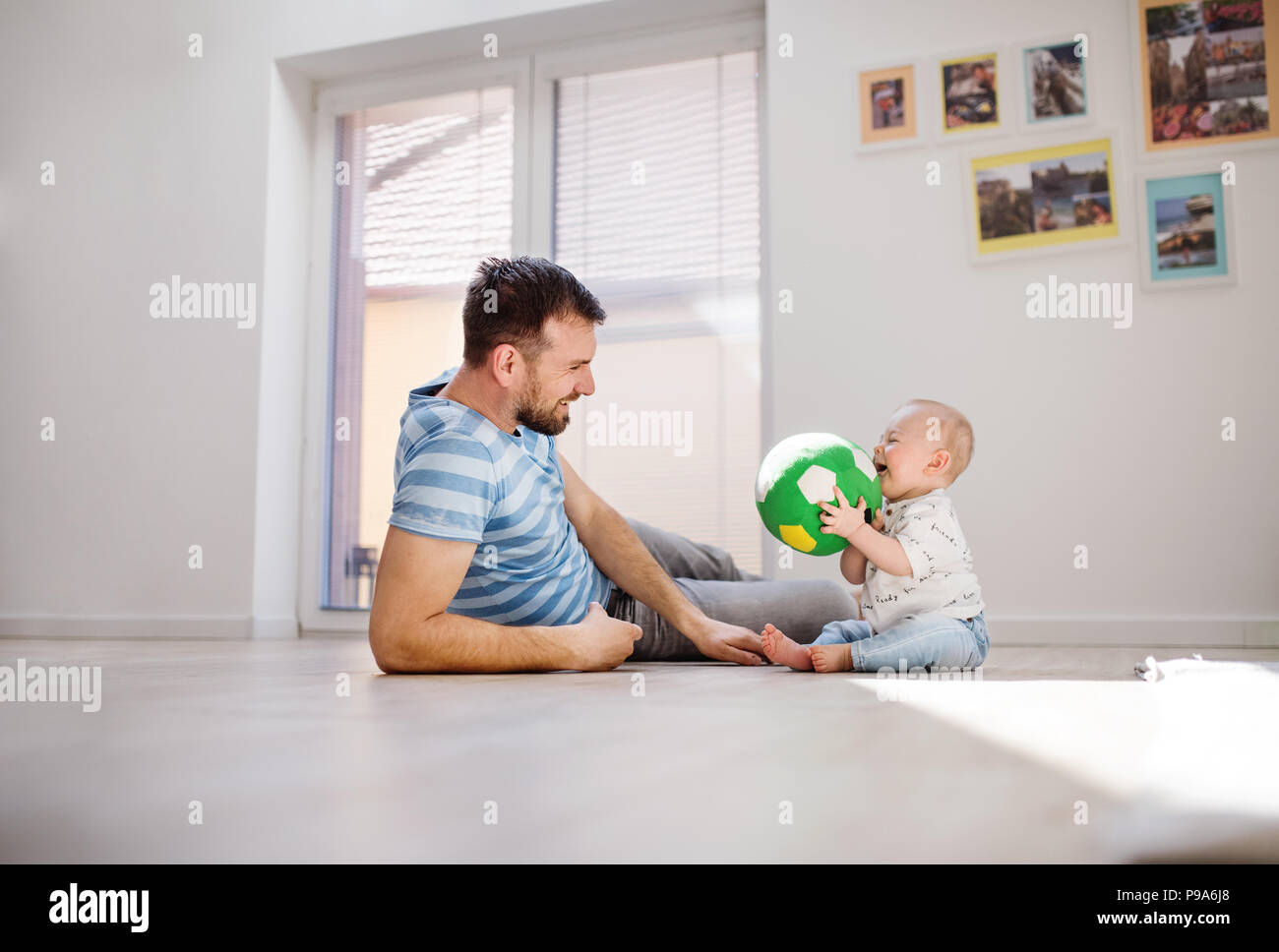 Young father playing with an unhappy baby son at home. Stock Photo