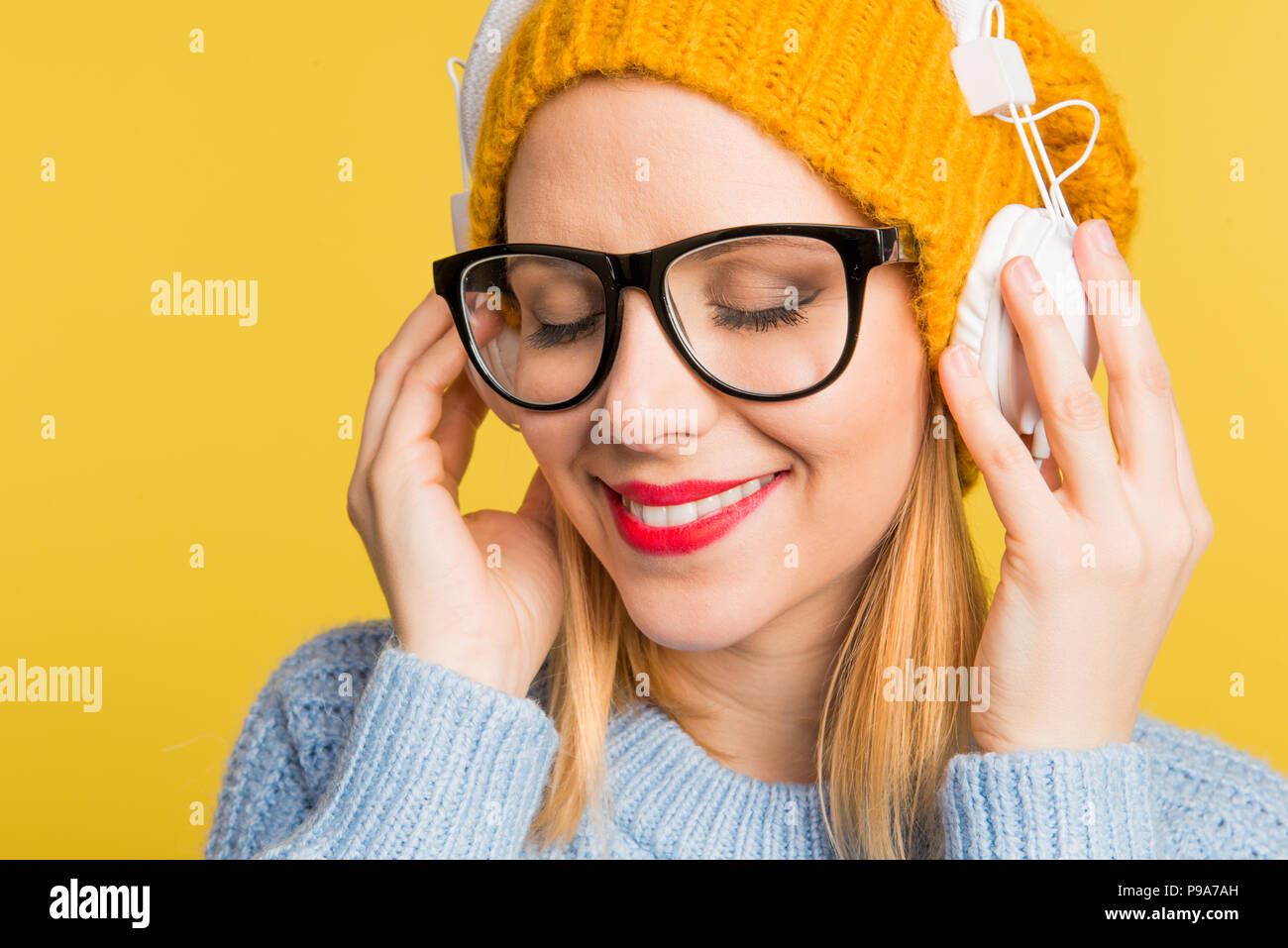 Portrait of a young beautiful woman with headphones in studio on a ...