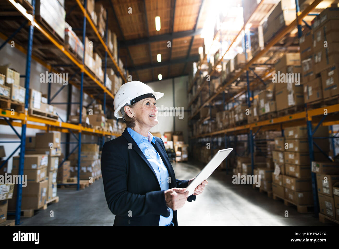 Senior woman warehouse manager or supervisor with tablet, working. Stock Photo