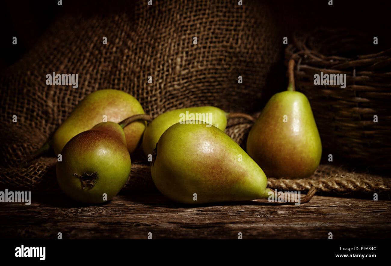 Fresh thigh pears on wooden rustic table with jute background. Stock Photo