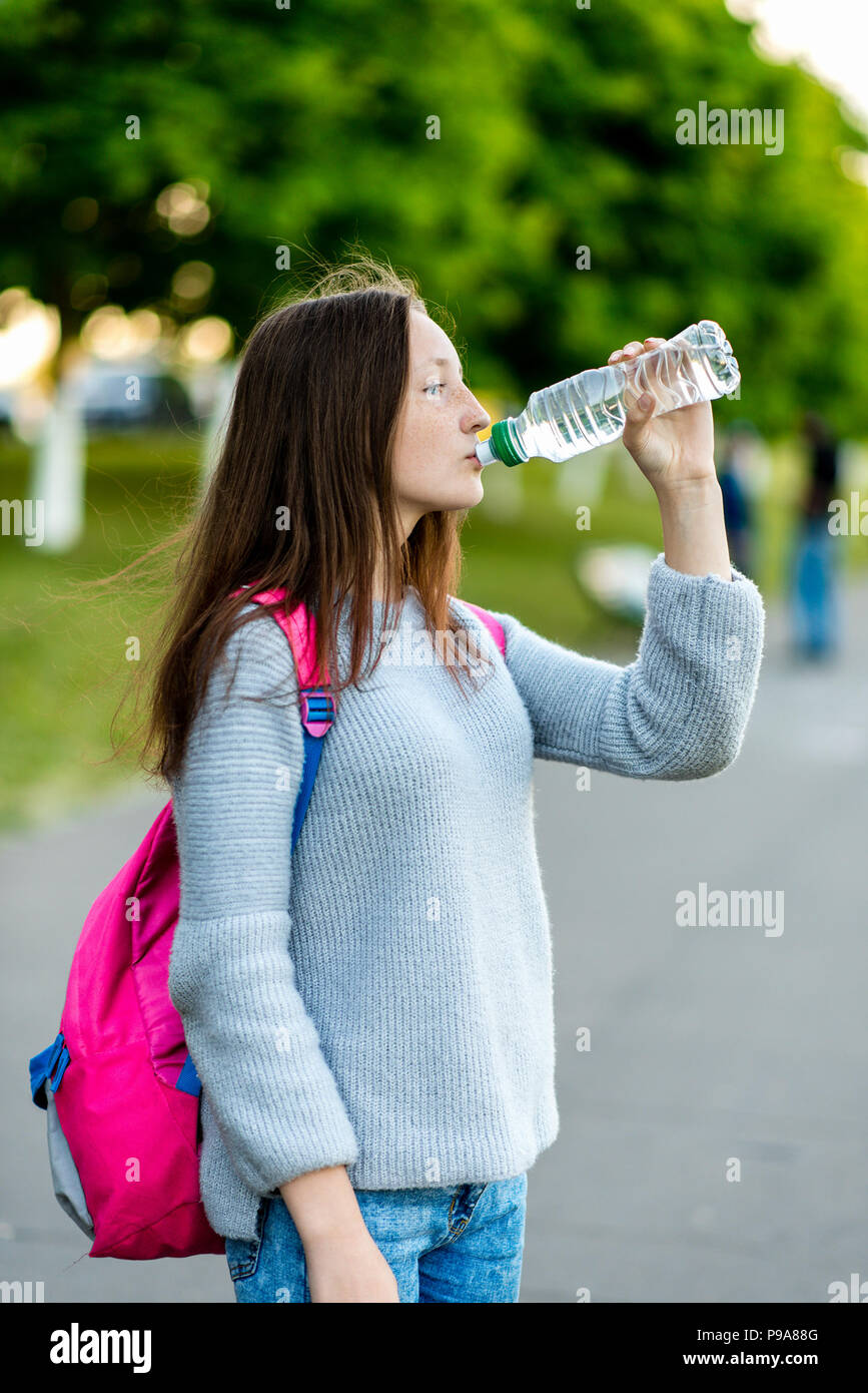 https://c8.alamy.com/comp/P9A88G/girl-schoolgirl-summer-in-the-city-on-street-he-drinks-water-from-the-bottle-behind-the-backpack-the-concept-of-lunch-after-school-emotions-thirst-for-pleasure-P9A88G.jpg